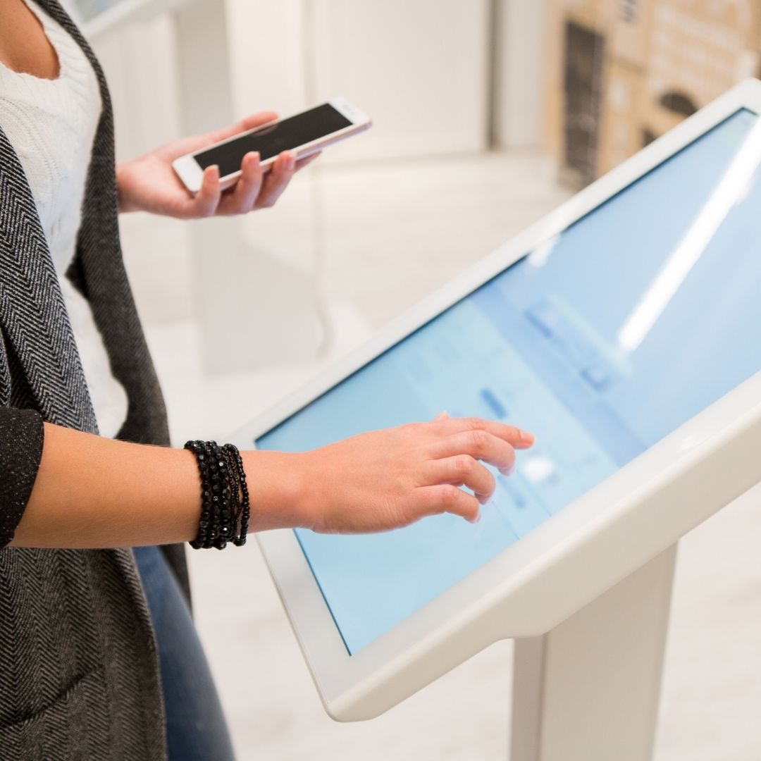 Image of a girl comparing her phone to a kiosk