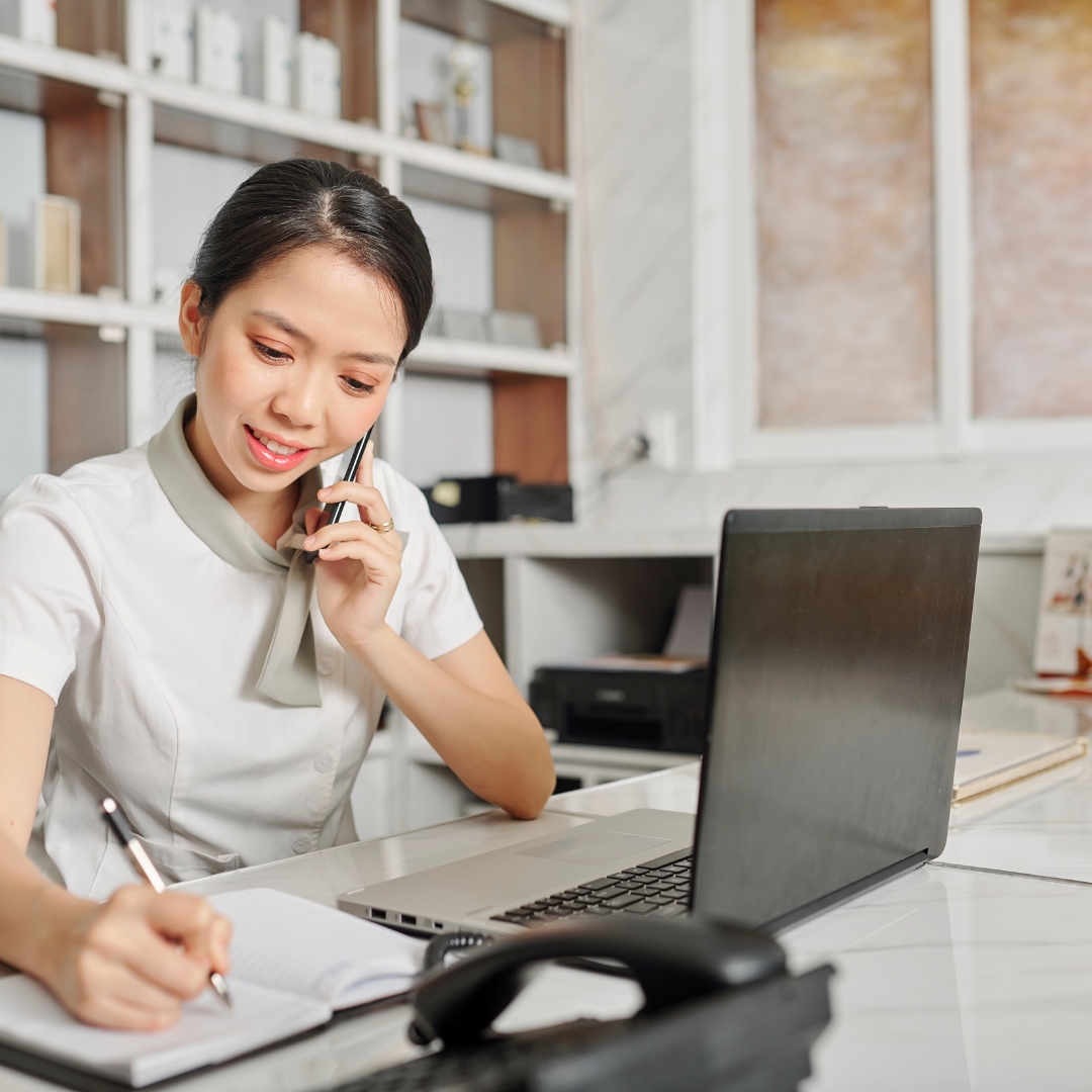 woman on phone with laptop in front of her